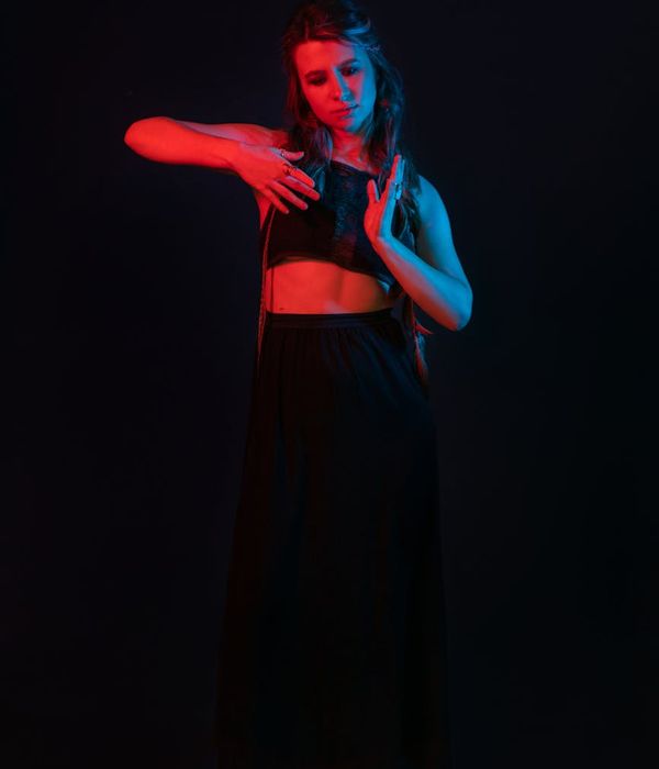 Woman in a graceful yoga pose focusing on joint mobility in a dark room.